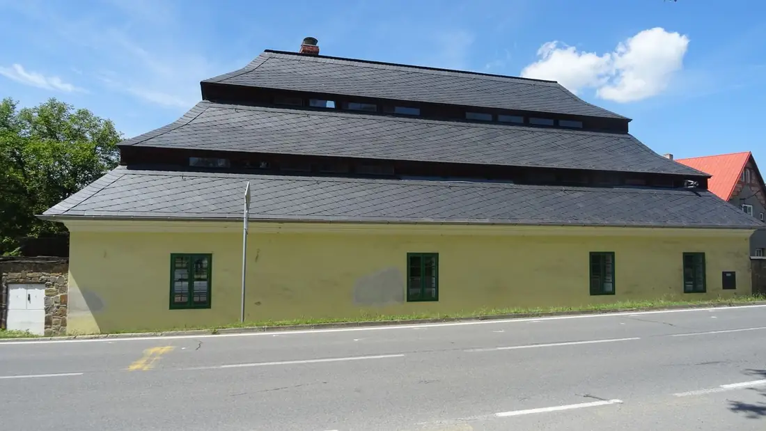 Žlutá budova Vošárny, bývalé zámecké prádelny, v centru obce.