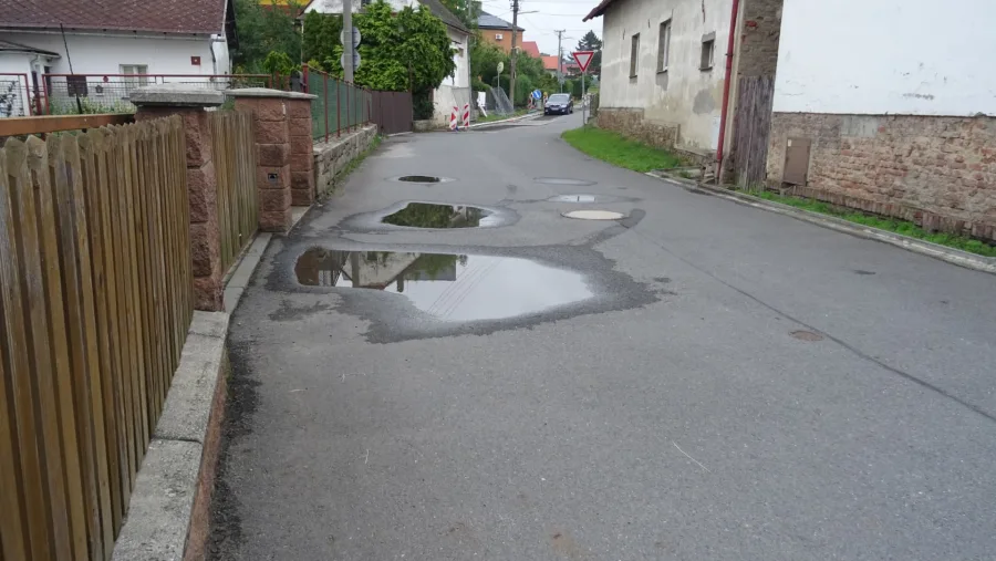 Ulice Polní v Raduni se stálou louží v prohlubni vozovky, která přetrvává více než šest let