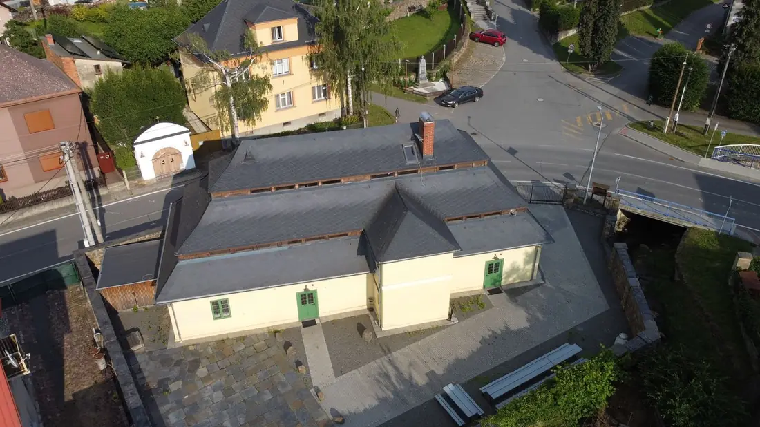 Pohled shora na žlutou budovu Vošárny a okolní zástavbu s ulicemi.
